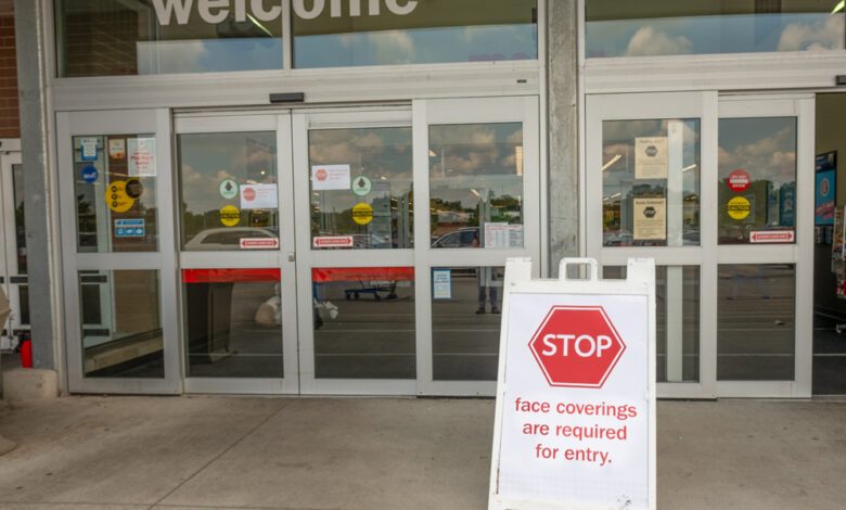 Stop sign at entrance to store requiring face masks before enter